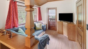 Een gezellige kamer met een houten bank, een televisie en een deur naar buiten.