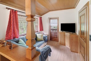 Een gezellige kamer met een houten bank, een televisie en een deur naar buiten.