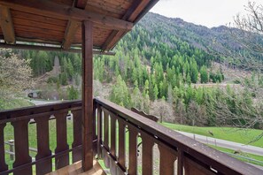 A wooden balcony with a view of a forested mountain and a road. - Apartment 'Sass De Stria' – Panoramic Views in the Dolomites near Arabba and Cortina (Cernadoi)