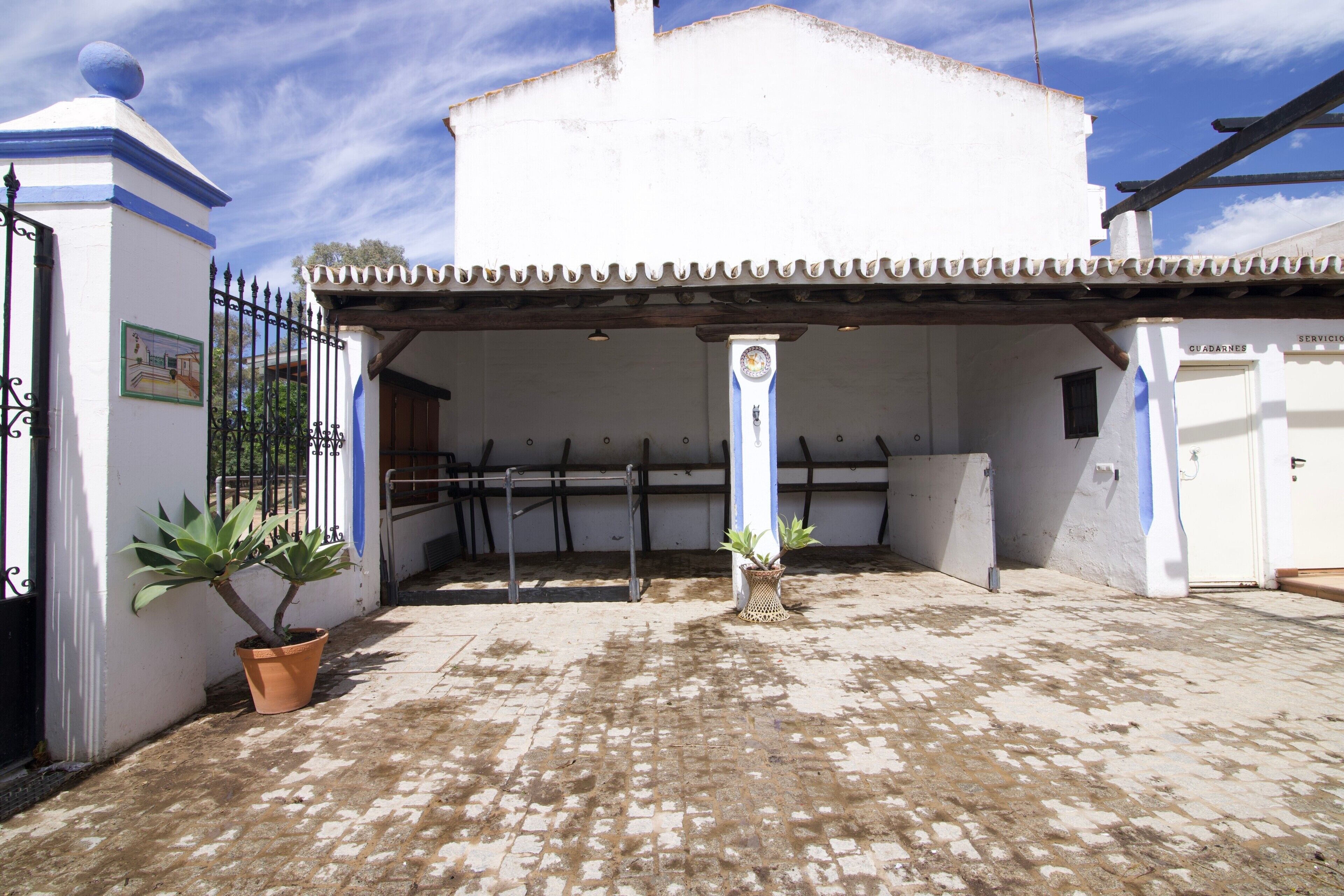 A building with a tiled patio, a white facade, and a blue door labeled 'GUARDIANES.'