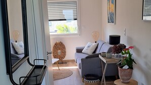 Een moderne woonkamer met een bank, salontafel, spiegel en een potplant.