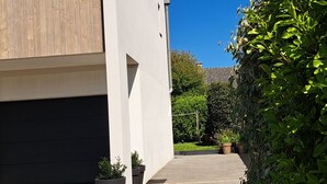 Een modern gebouw met een garage, potplanten en een helderblauwe lucht.