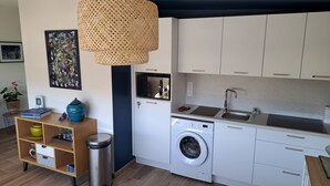 Een kleine keuken met een wasmachine, een magnetron en een spoelbak.