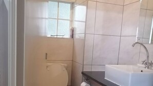 A bathroom with a toilet, sink, and a window. - Panaroma Home Nineteen (Graskop)