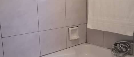 A bathroom with a bathtub, a towel rack, and a soap dish.