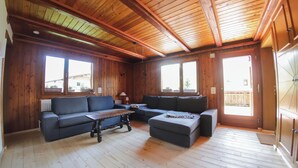 Een kamer met houten lambrisering, een bank, een poef en een tafel.