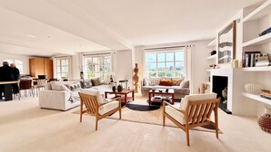 A spacious living room with a sofa, chairs, a coffee table, and a fireplace. There are large windows and a view of the outdoors. - 6 bedroom villa completely renovated in 2026 located between sea and countryside ✨ (Ramatuelle)