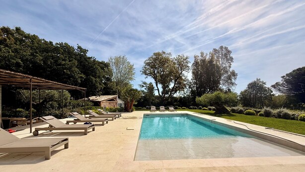 A swimming pool with lounge chairs, a covered seating area, and a building in the background. - 6 bedroom villa completely renovated in 2026 located between sea and countryside ✨ (Ramatuelle)