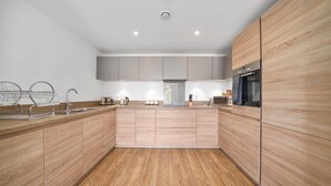 Una cocina moderna con armarios de madera, electrodomésticos de acero inoxidable y una isla central.