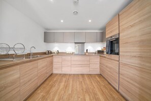 Eine moderne Küche mit Holzschränken, Edelstahlgeräten und einer Kochinsel in der Mitte.