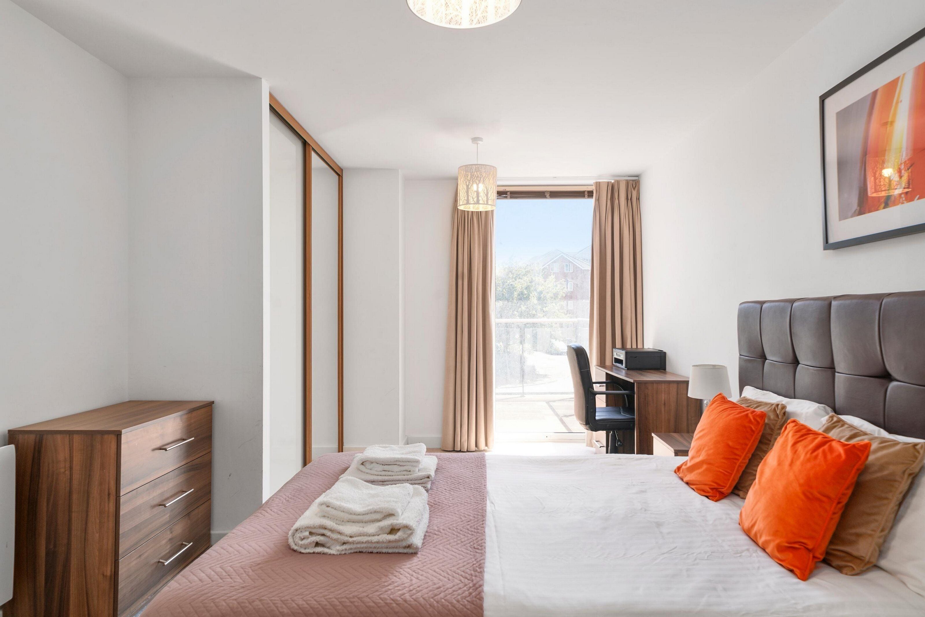 Una habitación de hotel moderna con cama, escritorio, silla y vistas al exterior.