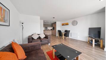 A modern living room with a brown sofa, a red rug, a black coffee table, and a TV on a wooden stand.