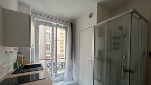 A modern bathroom with a glass shower enclosure, a sink with a countertop, and a view of the outside balcony. - La Folie Urban Room R Publique Marais Canal St Martin (Paris)