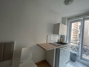 A compact kitchen with a built-in stove, a small sink, and a dishwasher. - La Folie Appartement r Publique Marais (Paris)