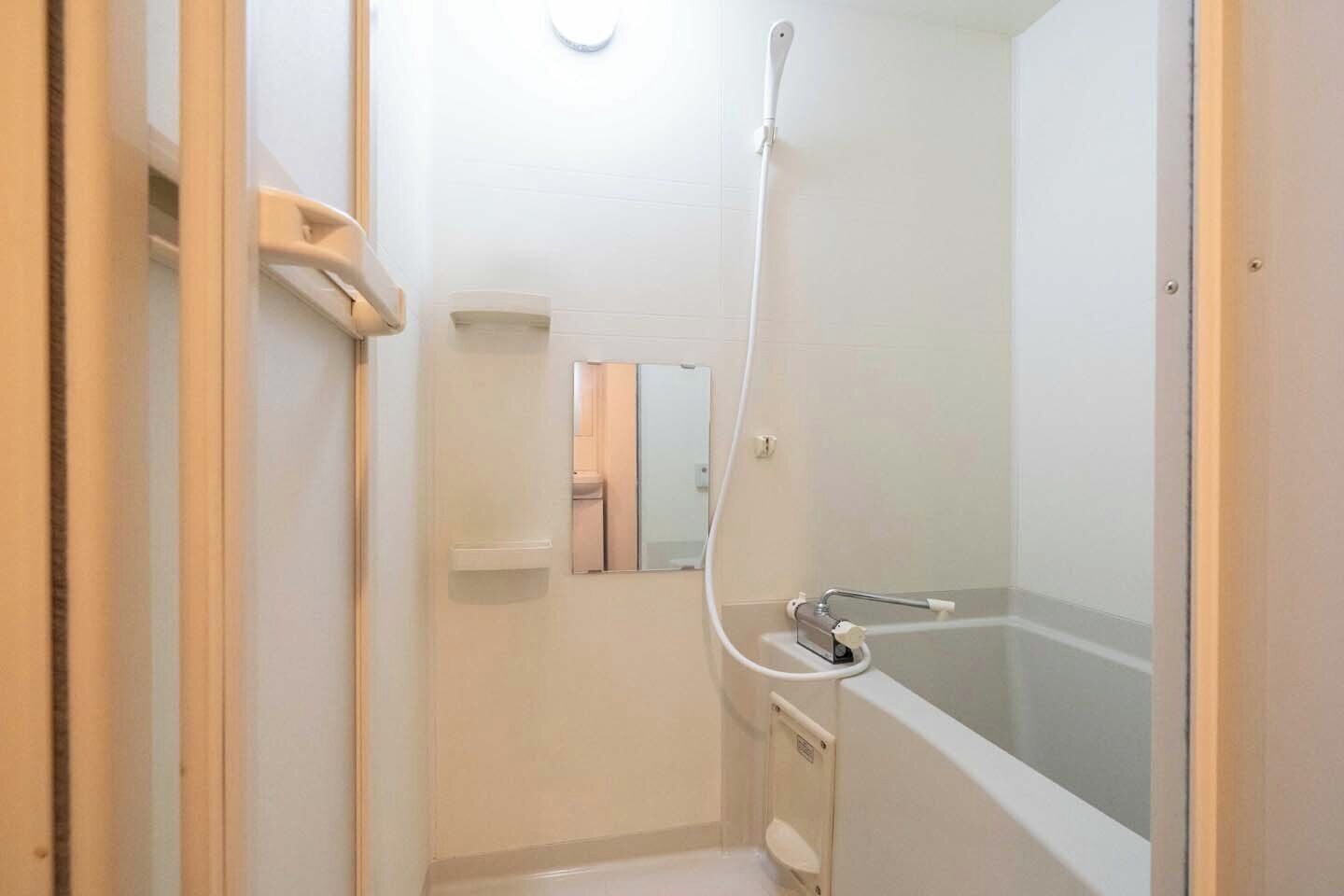 Une salle de bain avec une baignoire, une douche, des toilettes et un miroir.