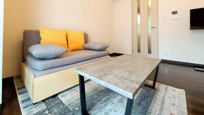 Ein modernes Wohnzimmer mit einer Couch, einem Couchtisch, einem Teppich und einem an der Wand montierten Fernseher.