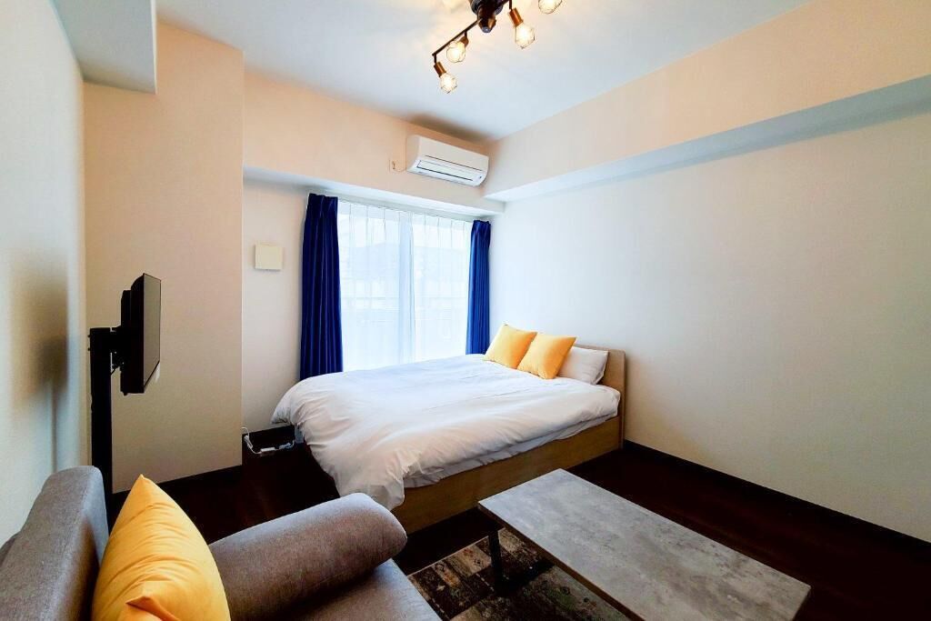 Un dormitorio con cama, sofá, televisión y aire acondicionado.