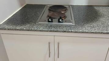 A kitchen with a gas stove, two cabinets, and a granite countertop.