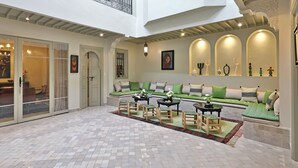 A spacious indoor courtyard with a high ceiling, a seating area with cushions, and a dining setup. - Riad Della (Marrakech)