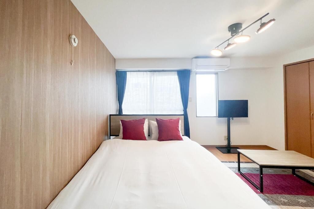 A hotel room with a bed, a desk, a lamp, and a wardrobe.