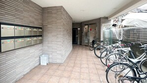 Een overdekt buitengebied met een rij kastjes, fietsen en een afvalbak.