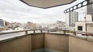 Een balkon op de hoek met uitzicht op een stadsgezicht, inclusief gebouwen en elektriciteitskabels.