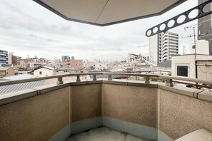Ein Eckbalkon mit Blick auf eine Stadtlandschaft, darunter Gebäude und Stromleitungen.