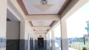 A corridor with a modern ceiling design, marble flooring, and a view of the outside. - Shubharambh Green's (Vrindavan)