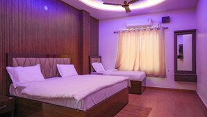 A bedroom with two beds, a ceiling fan, an air conditioning unit, and a mirror. - Shubharambh Green's (Vrindavan)