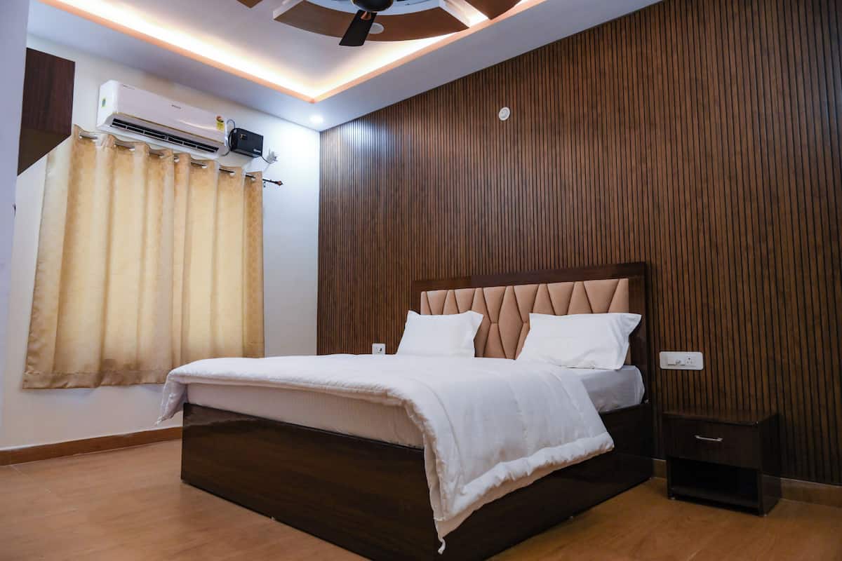 A bedroom with a bed, wooden panel walls, an air conditioning unit, and a nightstand.