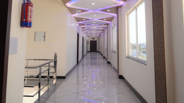 A hallway with a modern ceiling design, a fire extinguisher, and a window on the right. - Shubharambh Green's (Vrindavan)