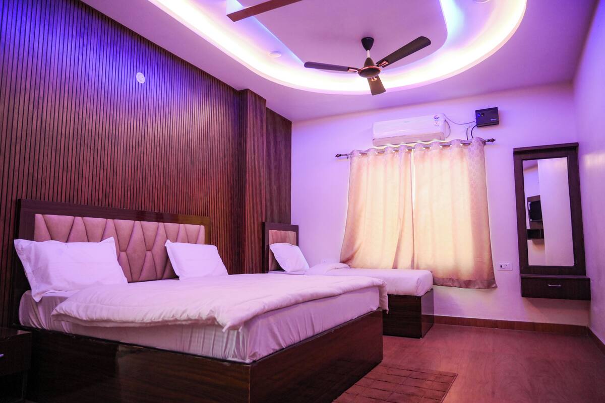 A bedroom with a bed, a ceiling fan, an air conditioning unit, and a mirror.