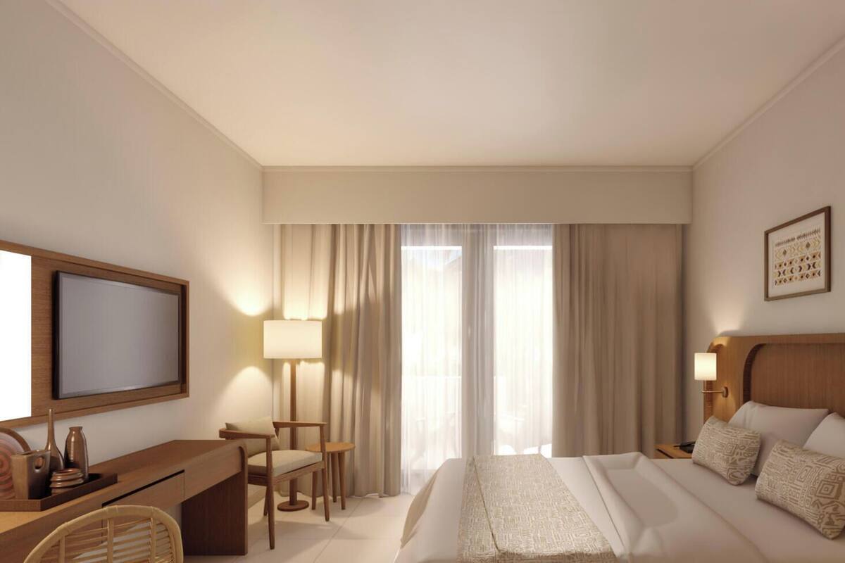 A hotel room with a bed, desk, chair, and a television.