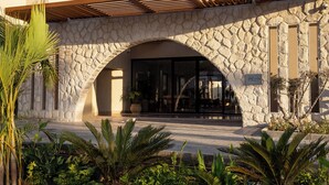 Fachada de piedra con entrada arqueada, un patio cubierto y un letrero que dice 'JAZ viva CASA MAZA'.