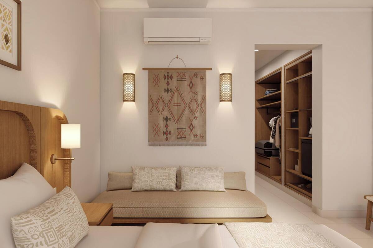 A bedroom with a bed, bedside tables, a wall-mounted air conditioner, a patterned tapestry, and a wooden wardrobe.
