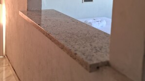 A room with a tiled floor, a white air conditioning unit, a small window, and a partial view of a bed. - Pousada Serra Azul (Juquiá)