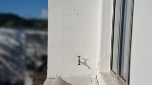 A small balcony with a white sink and window. - Pousada Serra Azul (Juquiá)
