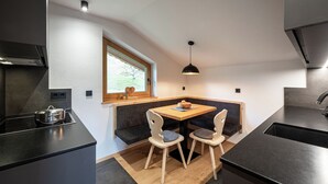Eine moderne Küche mit eingebautem Herd, einem Esstisch mit Stühlen, einem Fenster und einer Pendelleuchte.