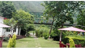 Un jardín con un puente, asientos exteriores y abundante vegetación.