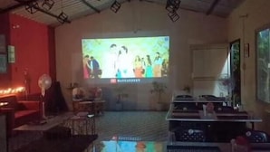 Una habitación con una pantalla grande mostrando una película, un ventilador y un piano.