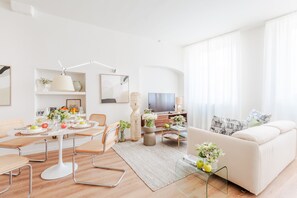 Ein modernes Wohnzimmer mit Essbereich, einer Couch und einem Fernseher.