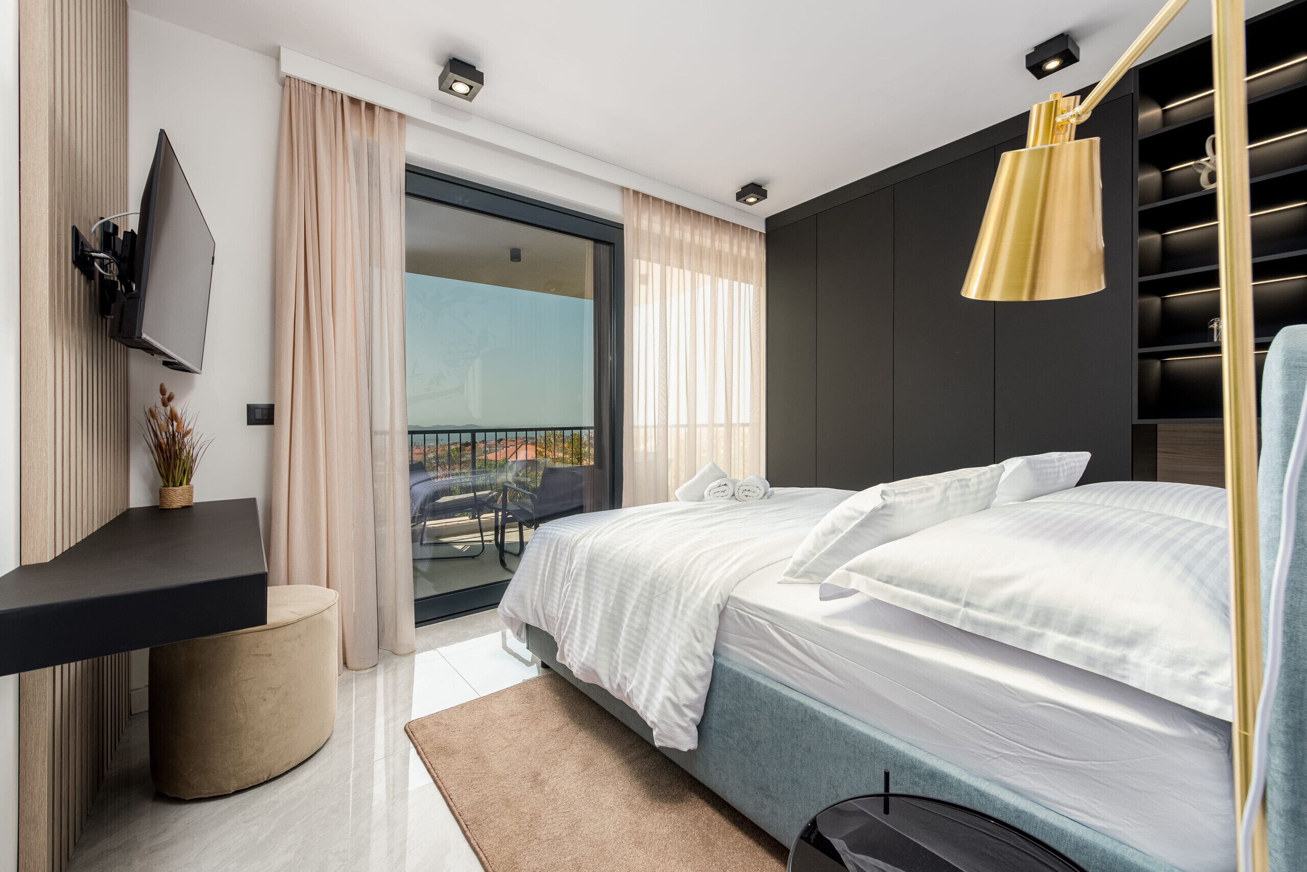 Une chambre d’hôtel moderne équipée d’un lit, d’un bureau, d’une télévision et d’un balcon avec vue.