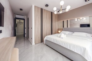 Ein modernes Schlafzimmer mit einem großen Bett, einem Schreibtisch und einem begehbaren Kleiderschrank.