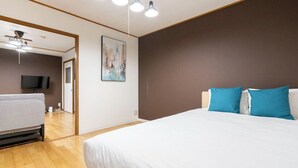 A bedroom with a large bed, a television, and a ceiling fan. - Urban Plaza (Osaka)