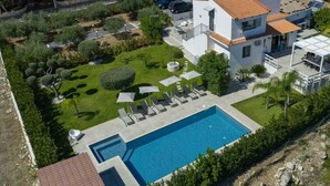 A modern two-story house with a swimming pool, surrounded by a well-maintained garden and a fenced property.