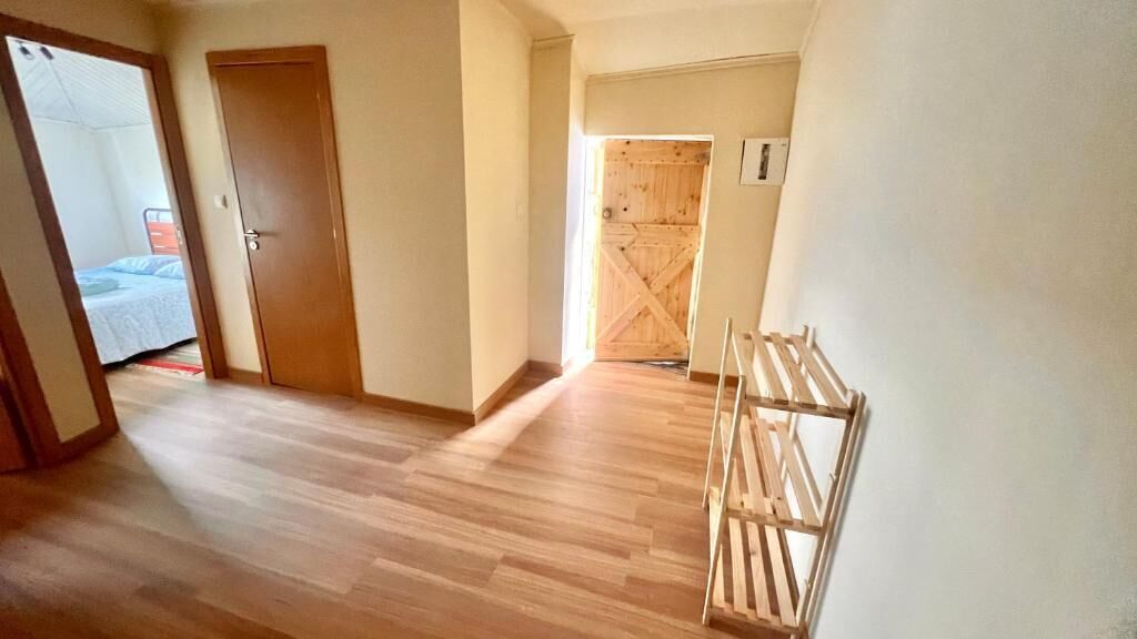 Un couloir avec un plancher en bois, une porte et un portail en bois.