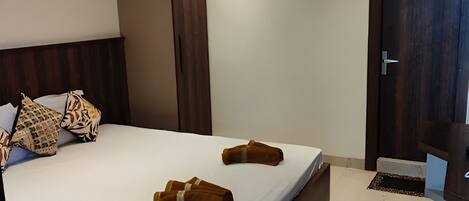 A modern bedroom with a large bed, a wardrobe, and a door.