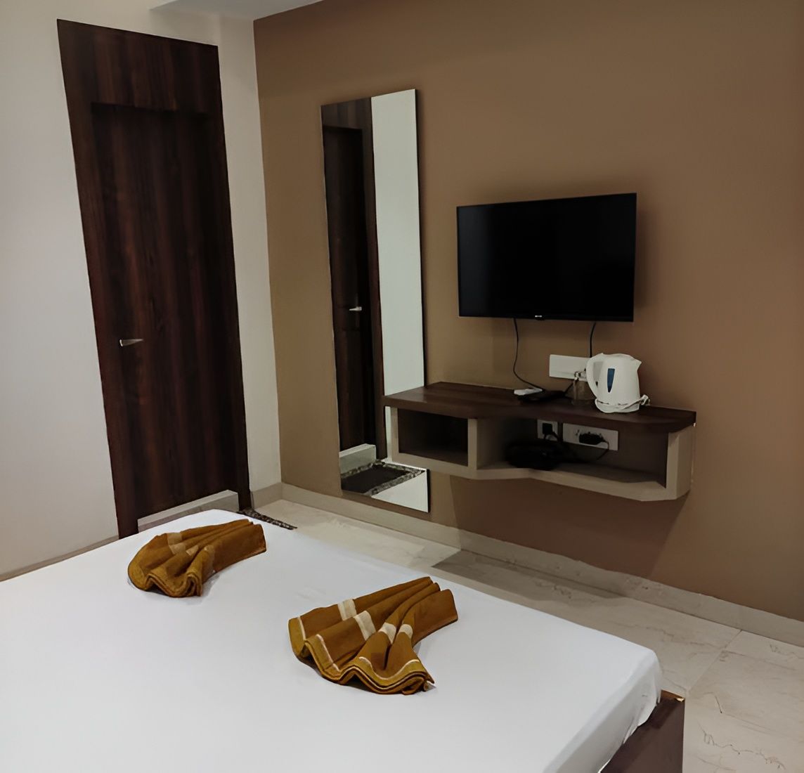 Habitación de hotel con una cama, un televisor de pantalla plana, cafetera y armario de madera.