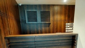 Una recepción con detalles de madera, un panel de control en la pared y suelo de baldosas.