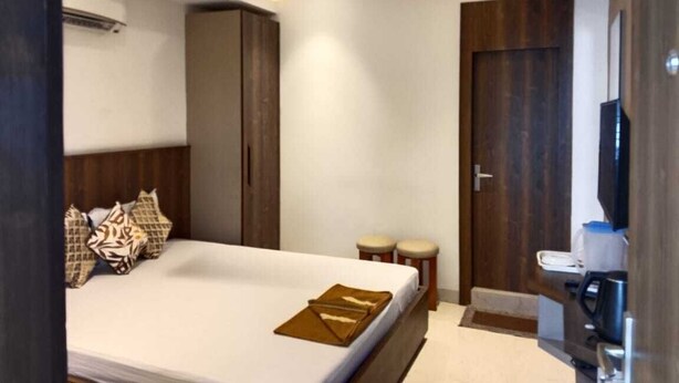Una habitación de hotel moderna con cama, ventilador de techo, armario, un pequeño rincón de descanso y baño.